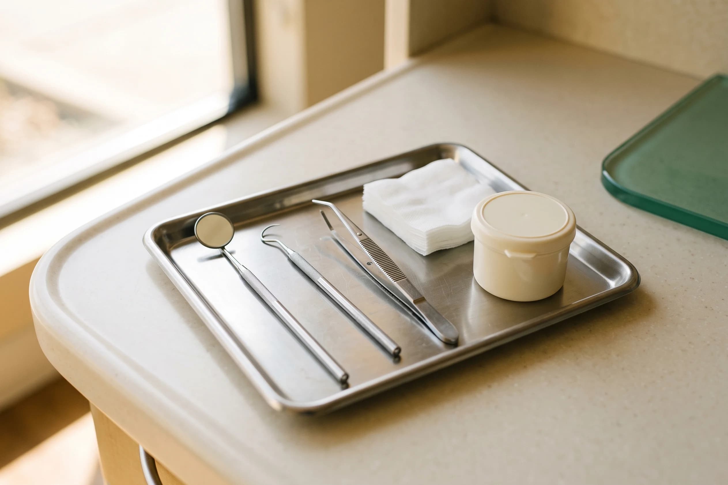 Illustrative dental instruments and aftercare supplies arranged on a stainless tray.