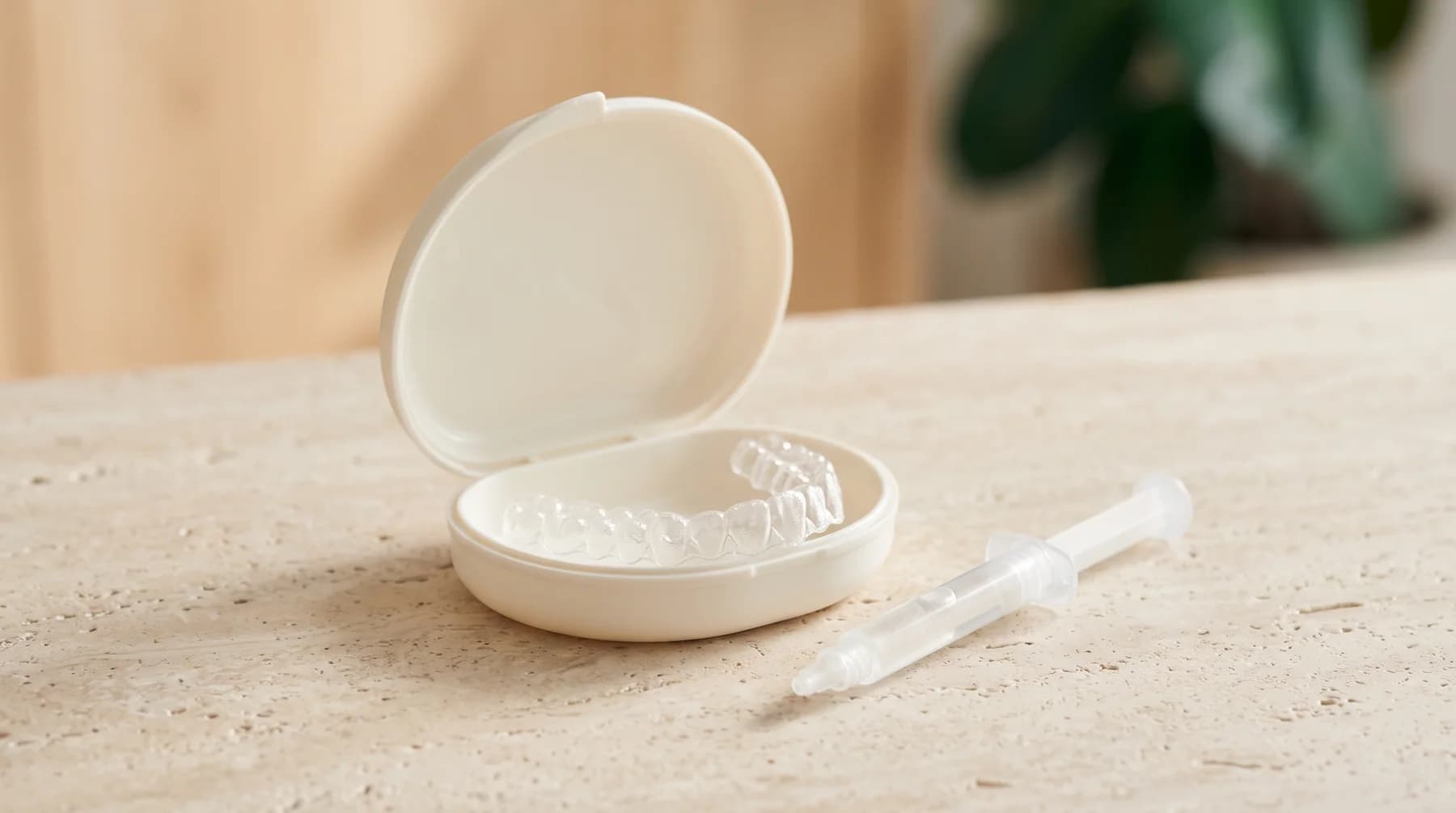Illustrative photograph of a transparent dental tray in a case beside a capped gel dispenser.