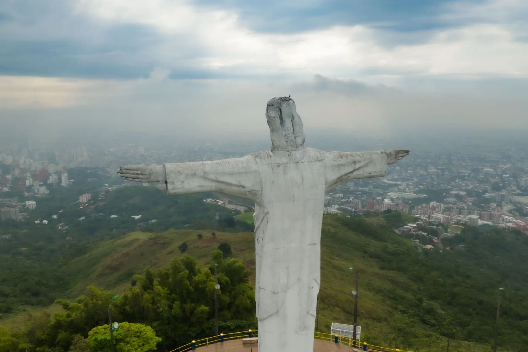 Cristo Rey overlooks the hills and city of Cali, Colombia beneath a cloudy sky.
