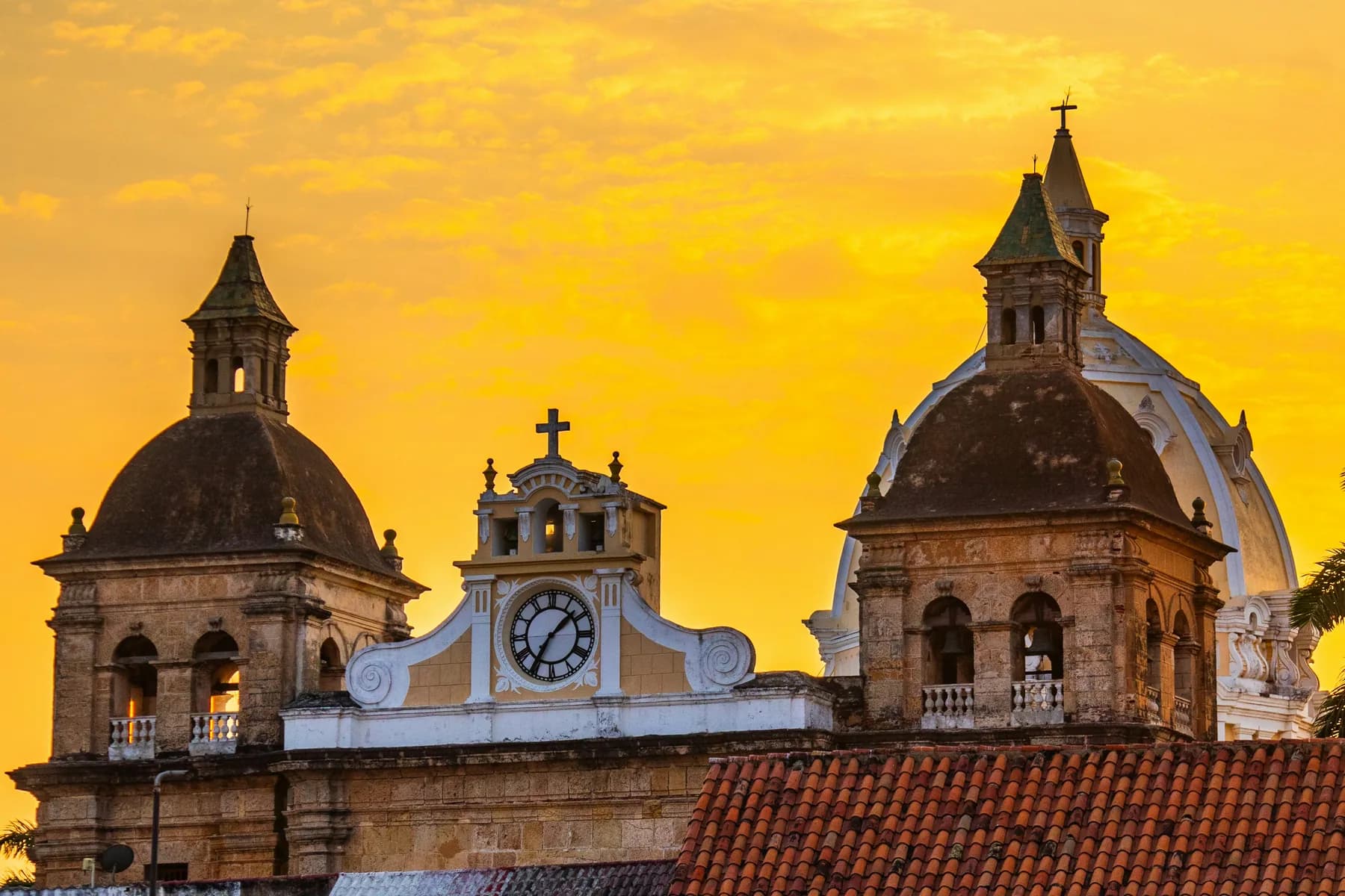 The bell towers and dome of Iglesia San Pedro Claver above tiled rooftops in Cartagena, Colombia.