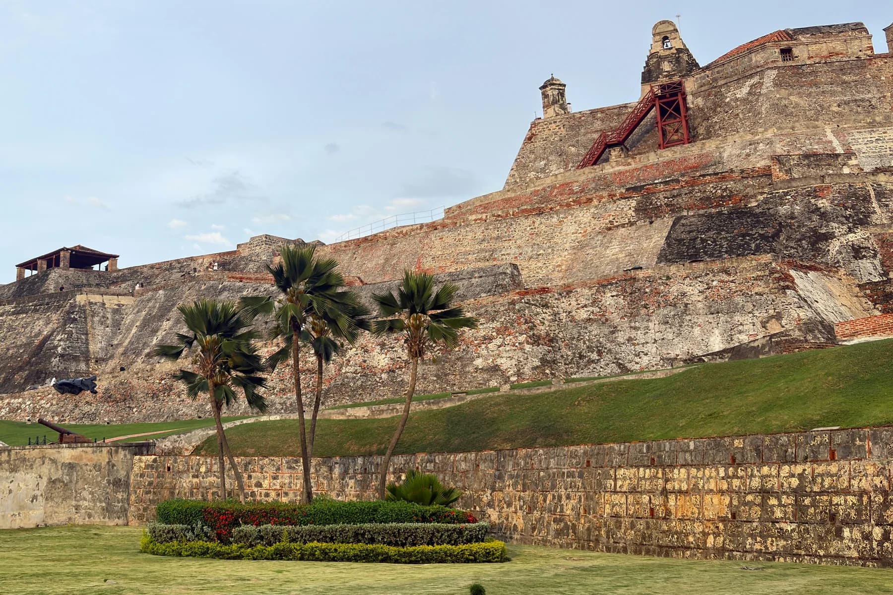 Stone walls, a bell gable and palm trees at Castillo San Felipe de Barajas in Cartagena, Colombia.