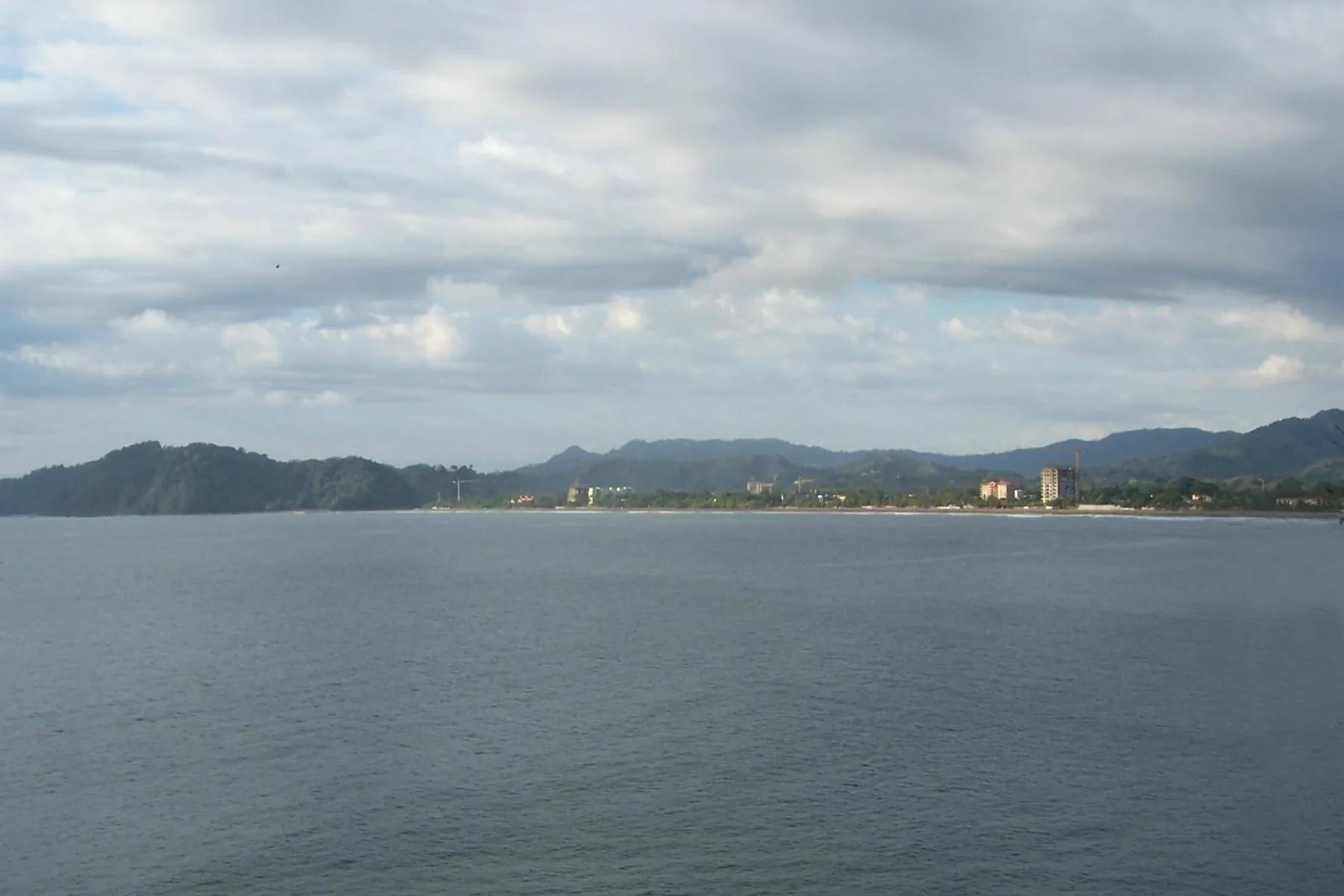 Jacó Bay curving past the beachfront town and forested headlands in Costa Rica.