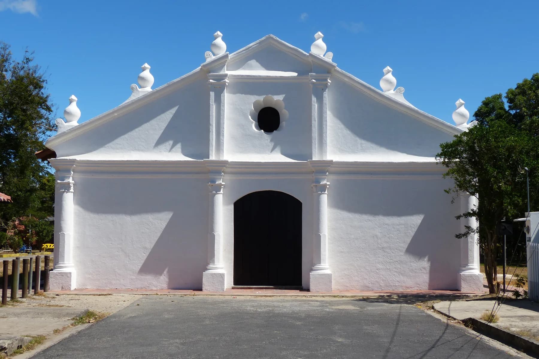 The white facade of La Ermita church beneath a clear blue sky in Liberia, Costa Rica.