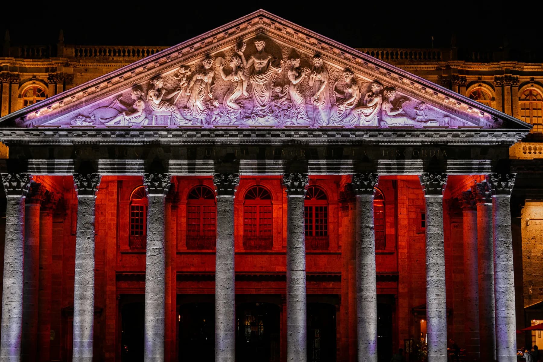 The illuminated neoclassical facade and sculpted pediment of Teatro Degollado in Guadalajara, Mexico.