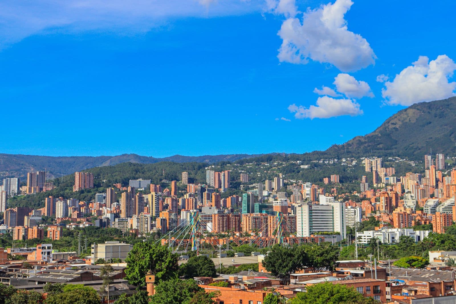 Medellín cityscape with the colorful Puente de la 4 Sur and mountains beyond.
