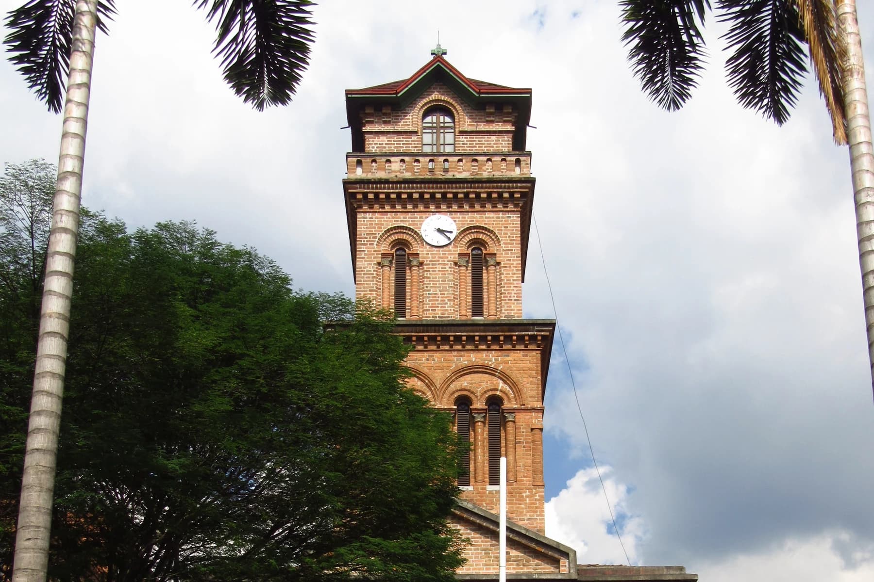 San José del Poblado clock tower framed by palms in El Poblado, Medellín.