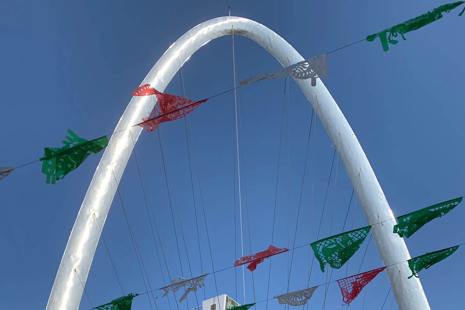 The silver Tijuana Monumental Arch framed by red, white and green papel picado near Avenida Revolución.
