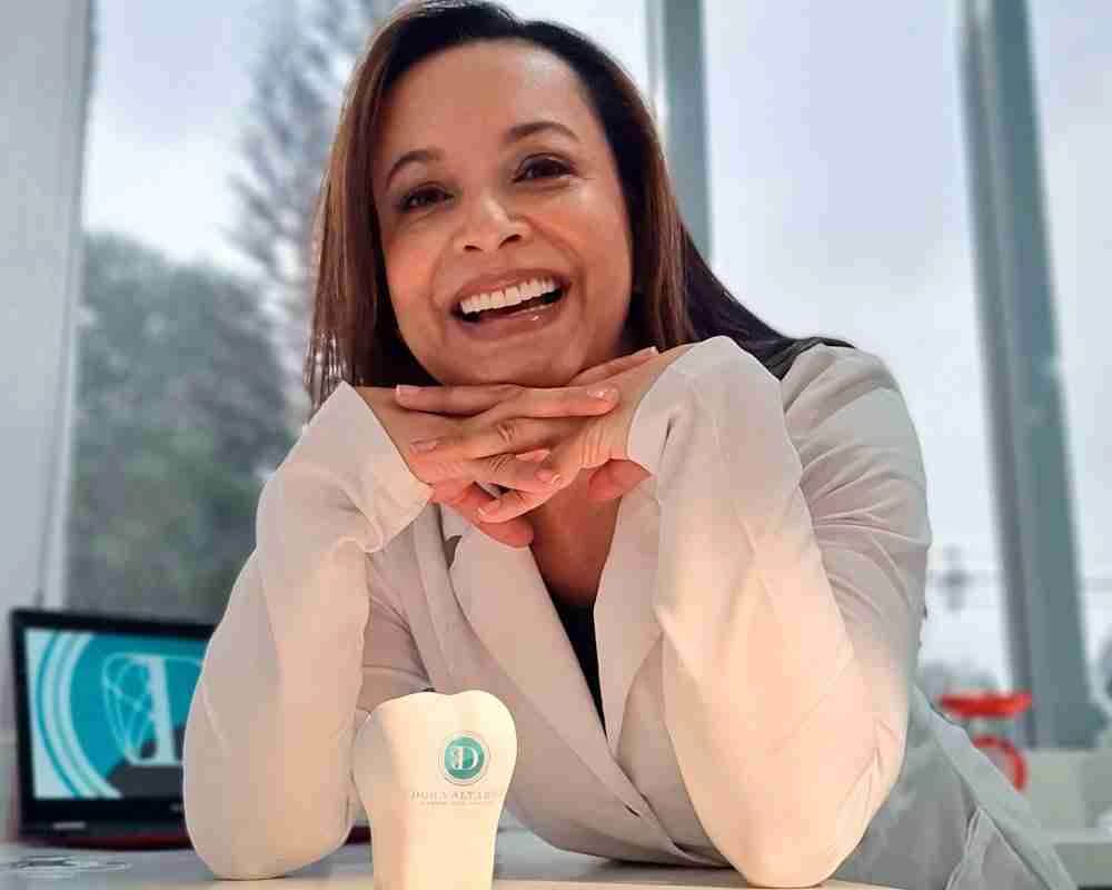 Dora Alvarez in a white clinical coat beside clinic branding