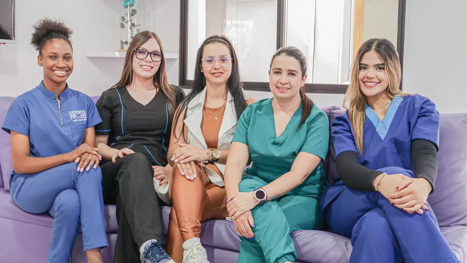 Five Odontopraxis team members seated together in clinic attire