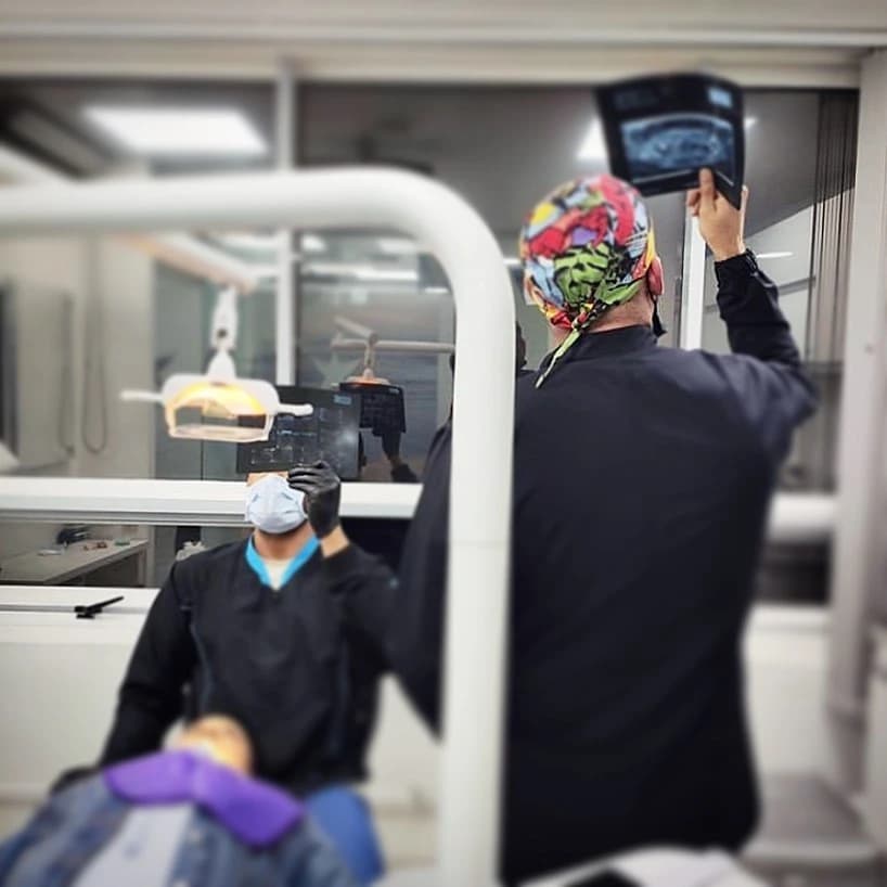 Two clinical workers with a radiograph beside a reclining person